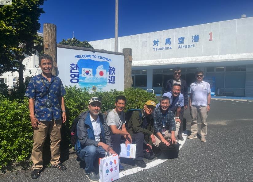 The AOPA Korea group outside the Tsushima Airport terminal, beside a sign reading Welcome to Tsushima.